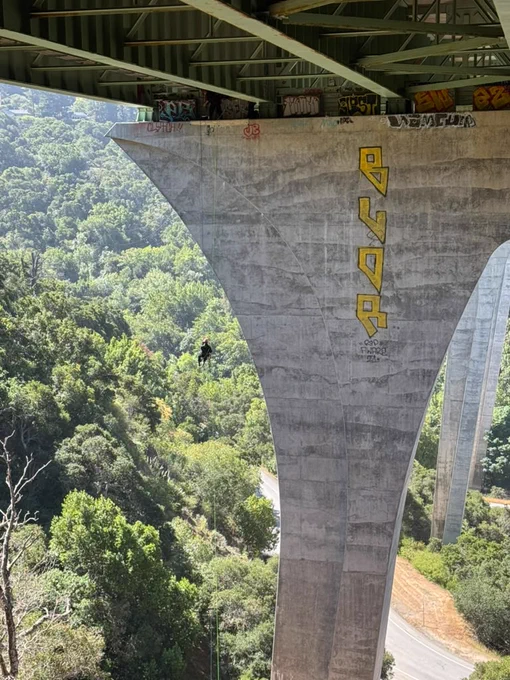 Firefighter rappelling off tall bridge