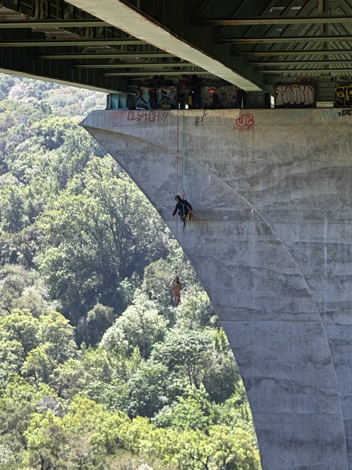 Firefighter rappelling off tall bridge with dummy