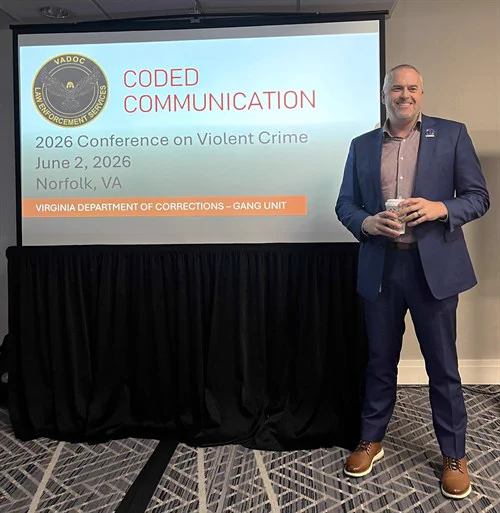 Mr. Diggs standing next to a screen displaying 'Coded Communication' at the 2026 Conference on Violent Crime in Norfolk, VA, hosted by Virginia Department of Corrections Gang Unit.