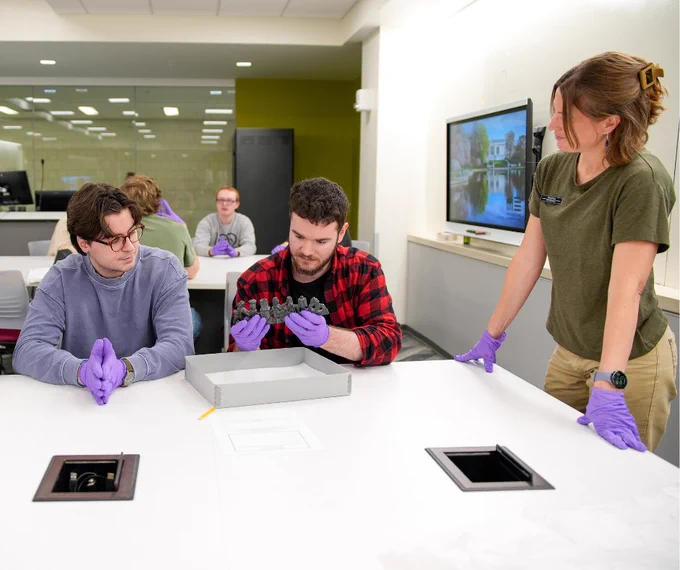 CSU students in an archeology class examining an artifact with a professor. 