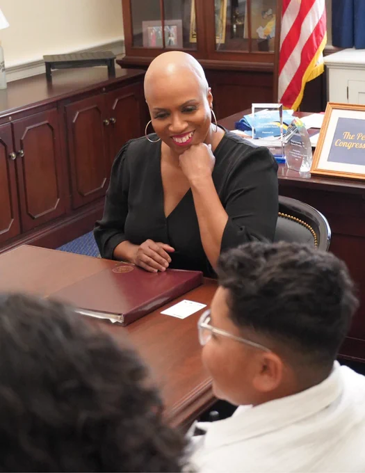 Rep. Ayanna Pressley smiles at Adrian during a meeting.
