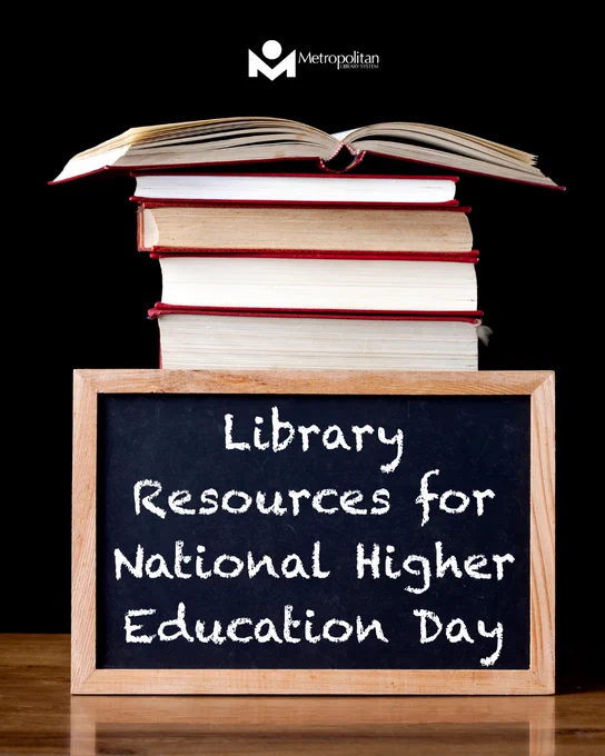 Stack of books with an open book on top behind a chalkboard reading 'Library Resources for National Higher Education Day.'