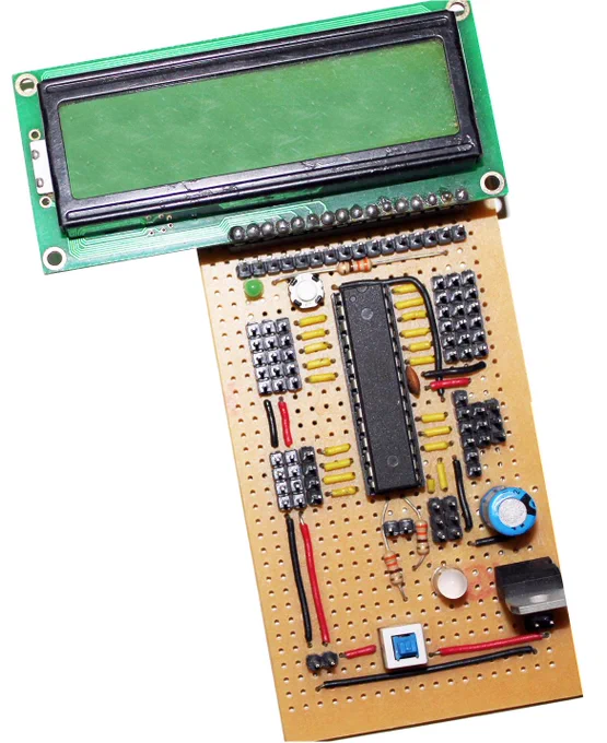 Photo of a handmade ATmega8 development board built on tan perfboard, with a DIP microcontroller, discrete components, jumper wires, and a green character LCD mounted above it.
