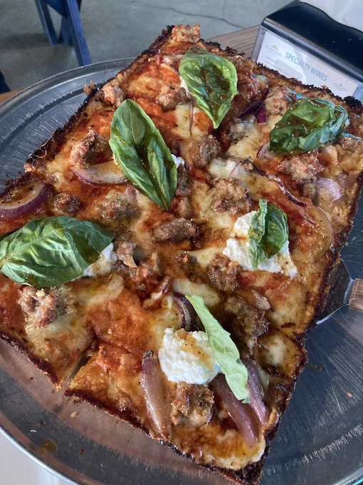 The Sunset Vodka Pizza featuring house-made vodka sauce, hot Italian sausage, red onion, ricotta, basil and hot honey. Finished with grated parmigiano reggiano.