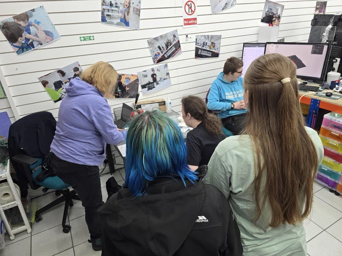 A group of young people learning how to use the badge making equipment.