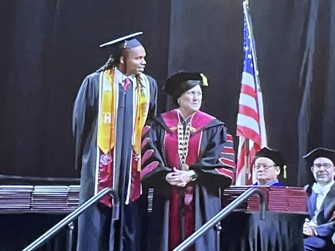 Graduate Kingston Christie at podium standing next to SPU President Porterfield.