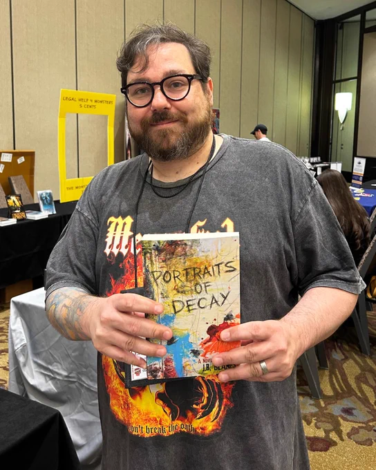 Photograph from StokerCon 2026 of J.R. Blanes holding a paperback copy of his novel Portraits of Decay.