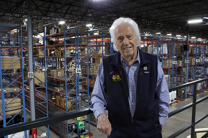 Jake Jabs standing inside one of his warehouses, smiling