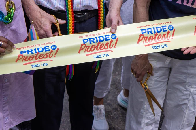 Senator Ed Markey holds golden scissors behind a ribbon reading" Boston Pride for the People, Pride As Protest! Since 1776"