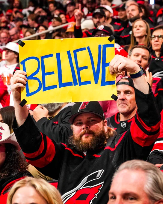 Photo of a fan holding a sign that says BELIEVE 