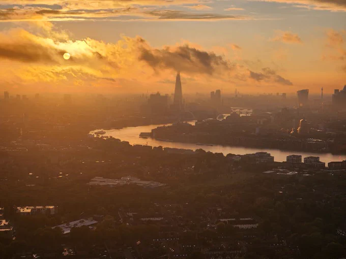 A stunning aerial view of London's skyline at sunset featuring the Shard and the Thames River.