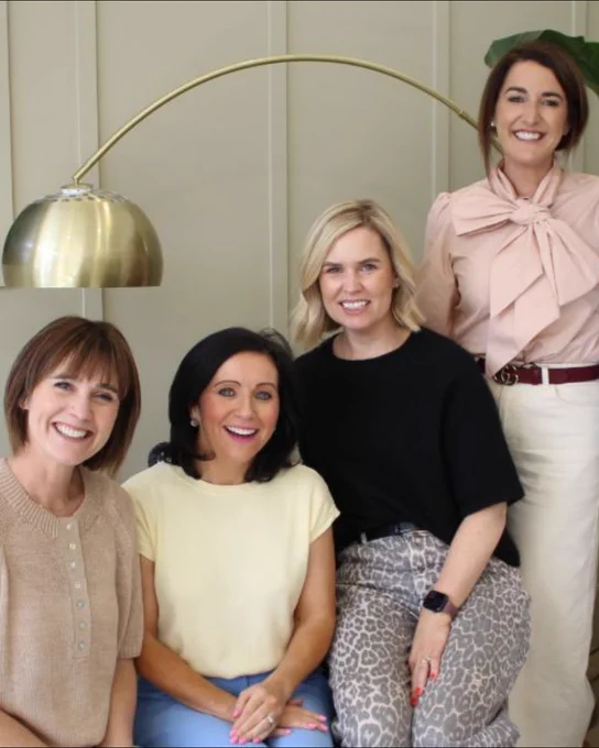 Team photo of five colleagues seated and standing together in a modern office, with a Cooper Parry screen in the background.