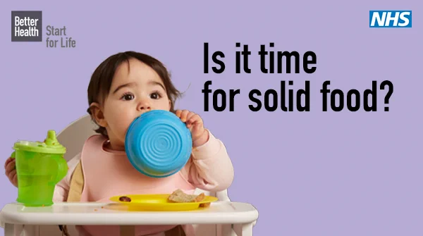 Advertisement by NHS with a baby in a highchair, biting a blue cup, with the caption 'Is it time for solid food?' and solid food items on the tray.