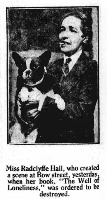 Black and white image of Radcliffe Hall. She is shown smoking a cigar, wearing a masculine style suit, and holding a dog. The caption reads: 'Miss Radclyffe Hall, who created a scene at Bow street yesterday, when her book, 'The Well of Loneliness,' was ordered to be destroyed.