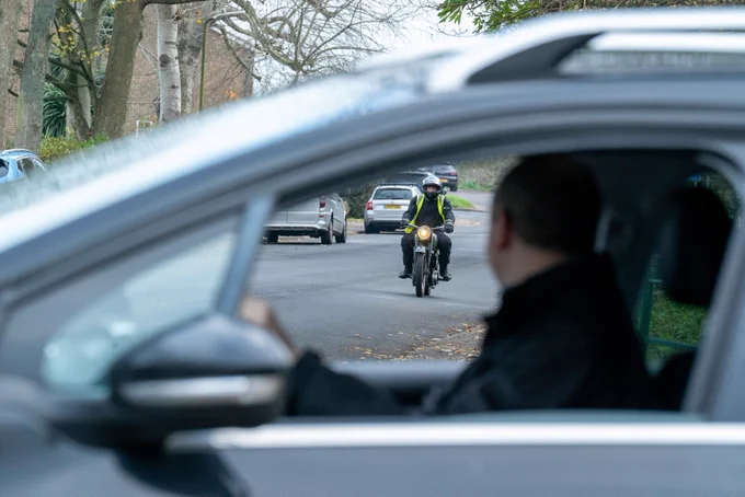 A car and motorbike on a road.