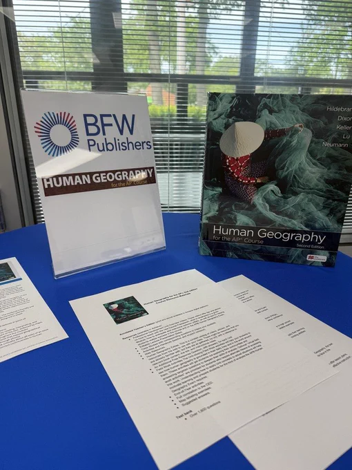 Human Geography curriculum materials being considered sitting on a table with books info sheets.