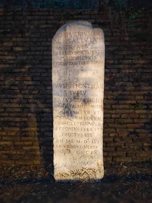 REPUBLICAN CIPPUS, MID-C1 BCE, REUSED BY PAUL IV, 1557. VICO JUGARIO

Standing by a wall below the Capitoline cliff, this vertical block of weathered cream travertine bears two eras of text on its flat face. At the top, Republican treasury prætors note using public funds to buy back private land to secure a road. Beneath, Pope Paul IV carved a text in 1557 during a destabilising war with Spain. With an invading army at the gates and Rome panicking over a second sack, the austere Carafa pope hijacked this stone. Though he loathed classical statues, hiding the Vatican collection from public view, he loved Roman law. He used this legal marker to graft papal authority onto ancient Republican civic jurisdiction, projecting absolute control while his pontificate descended into riot, starvation, and corruption. Remarkably, this text survived the violent riots and systemic erasure of the Carafa name that erupted immediately after his death in 1559, enduring quietly on a street corner.