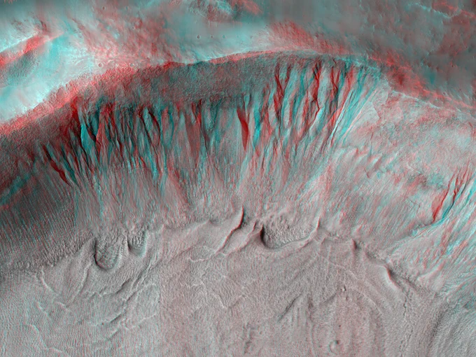 3D image shows a steep impact crater rim with numerous, well-defined gullies extending from near the top down to the flatter bottom of the crater.