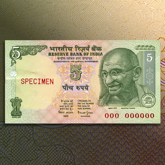 Billet de banque vert, motifs roses, homme chauve portant des lunettes rondes : le Mahatma Gandhi.