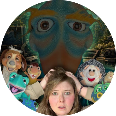 A person with hands on their head is surrounded by several puppets, with a large dino puppet face looming in the background.