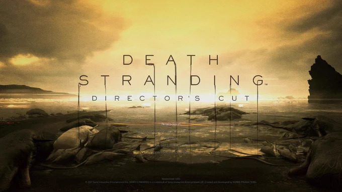 Titelbildschirm von Death Stranding Directors Cut. Ein goldener Himmel erstreckt sich über einen dunklen Strand voller gestrandeter Wale. In der Mitte prangt das Logo des Spiels über den Hauptmenüpunkten.