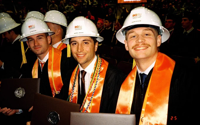A group of graduates in regalia, wearing white hard hats and orange stoles, smile while holding diplomas. In the background, there are many other seated graduates. The second part of the image shows an indoor graduation ceremony at Bowling Green State University with a large audience and stage. Banners and decorations hang overhead.