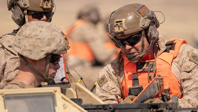 Marines in tactical gear review a mission checklist while positioned in a light armored tactical vehicle during convoy operations training.