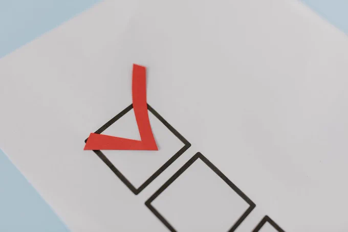 Close-up of a red check mark on a crisp white paper with black boxes, symbolizing completion.