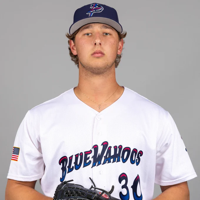 Karson Milbrandt poses in a white Pensacola Blue Wahoos jersey and blue cap