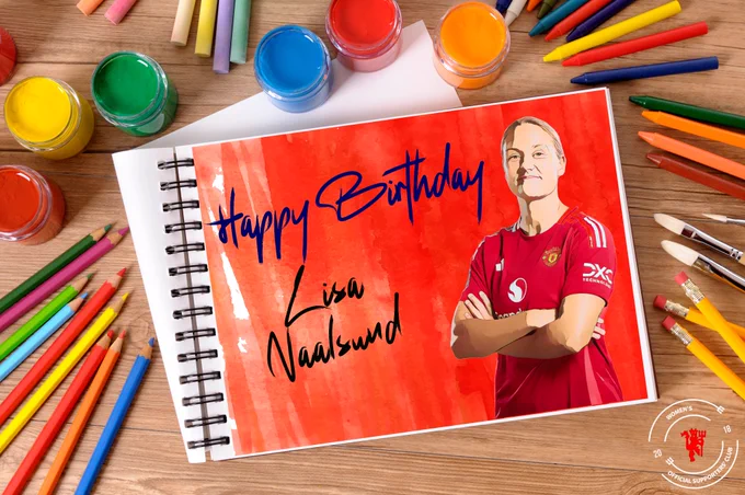 Lisa Naalsund with folded arms stood next to a “Happy Birthday” message, written on a paper pad surrounded by coloured pencils, paint pots, brushes and crayons. 