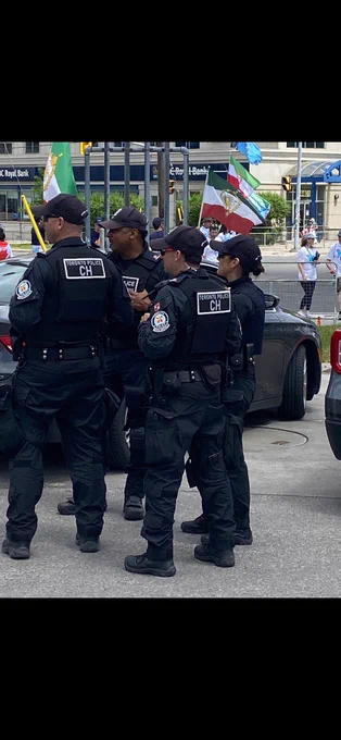 Members of the Public Order Unit. In the background are vehicles and flags.