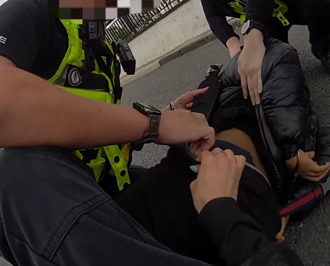 Suspect being detained on floor and a weapon being taken off him.