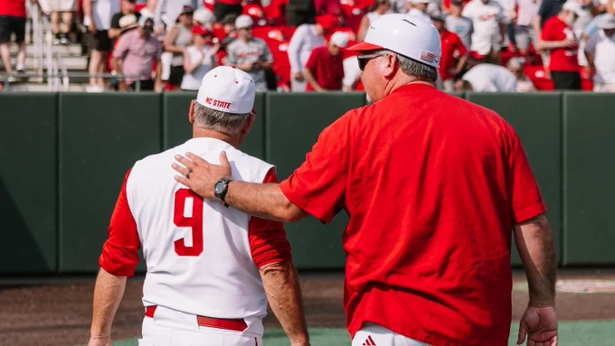 Chris Hart in red shirt and cap pats Elliot Avent wearing number 9 jersey on the back during a game.