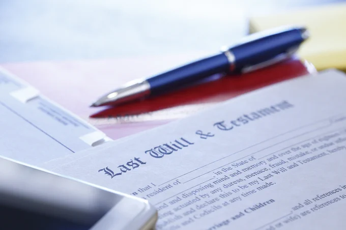 Close-up of a last will and testament document with a pen resting on a folder, symbolizing legal planning.