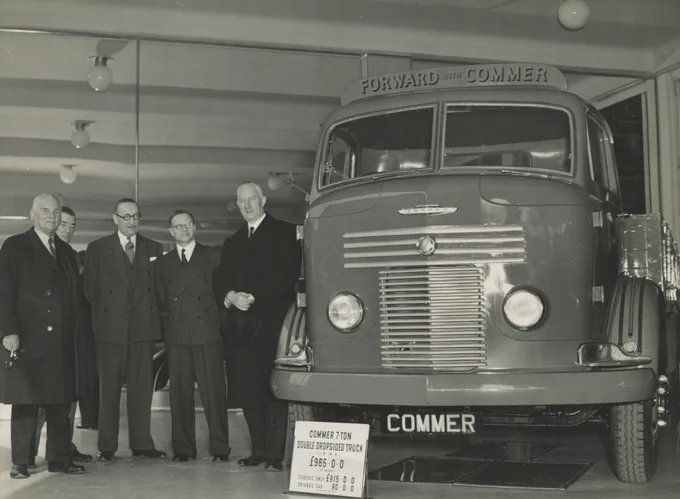 a group of four men standing together and admiring a Commer 7-ton truck