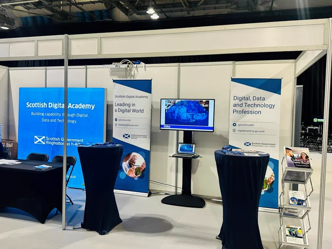 image showing Scottish Digital Academy exhibition stand with tables and signage. 