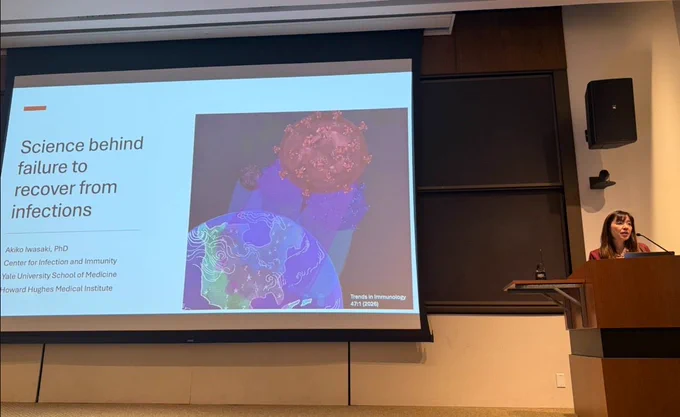 On the wall, a presentation named « Science behind the failure to recover from infections » 
At the right, A. Iwasaki is talking
