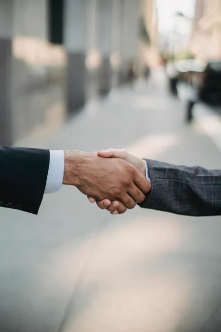 Una foto en primer plano de dos personas dándose la mano en señal de acuerdo.
