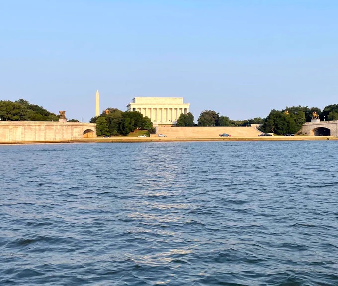 View of the Lincoln Memorial and Washington Monument across the calm waters of the Potomac River on a clear day.