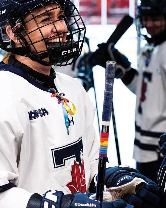 Photo of  a Toronto Varsity Blues women's hockey player with Pride on her stick and the Pride lace on her jersey 