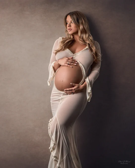 Phoenix Maternity Photography: Beautiful Pregnant woman with her hands on her belly, wearing a cream belly cut out dress.