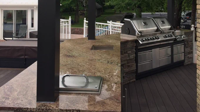 Custom outdoor kitchen built by Deck City featuring stainless steel built-in grills, stone finishes, and granite countertops on a backyard deck.