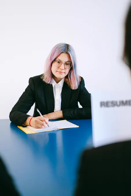 Una mujer sentada en una mesa firmando unos documentos.