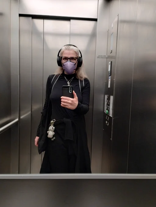 Mirror selfie in an elevator wearing a light purple Rackmask 