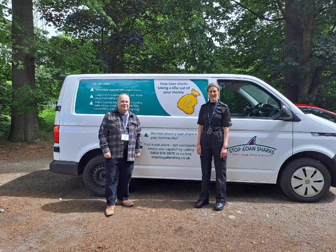 Two people stand in front of a "Stop Loan Sharks" van offering support and advice.