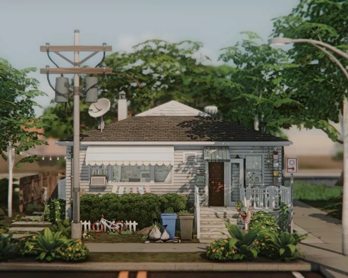 A front view of a NoCC (CC-free) single-story house in The Sims 4, featuring vintage striped window awnings and a dark wood front door. This house is inspired by a real-life home.