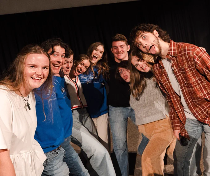 group of people smiling and making silly faces, having a good time