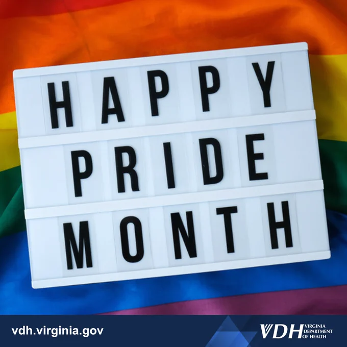 Lightbox sign displaying 'HAPPY PRIDE MONTH' over a vibrant rainbow flag background.