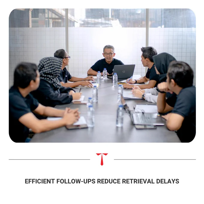 An image of a diverse group of professionals engaged in a focused meeting around a conference table with laptops and documents, representing efficient follow-ups and team collaboration. 