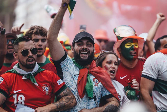 Group of enthusiastic Portuguese soccer fans celebrating outdoors.